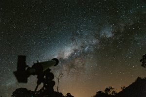 Silhouette of a telescope with a stunning Milky Way background in the night sky.